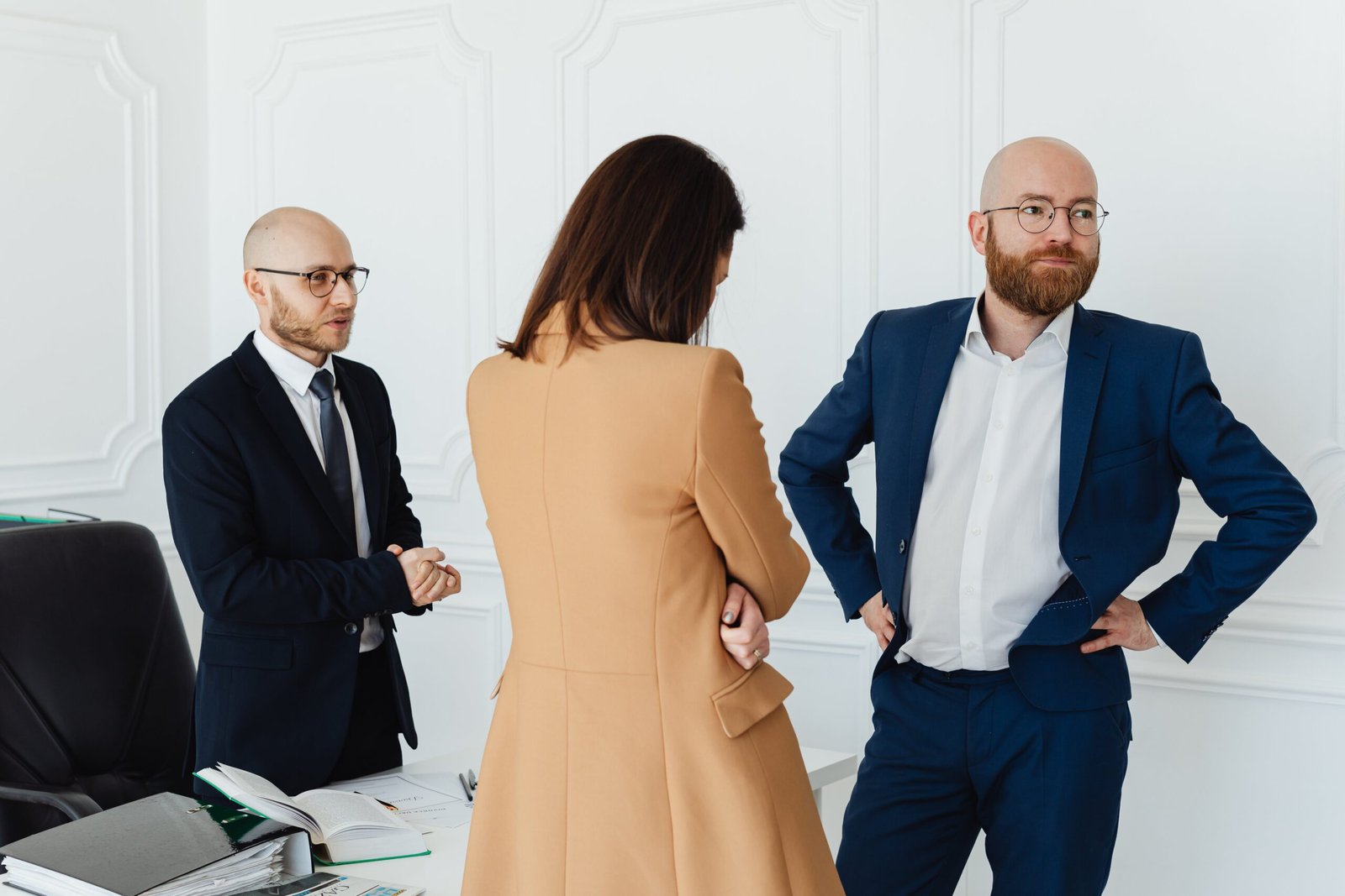 A professional trio engaged in a serious discussion inside a modern office.